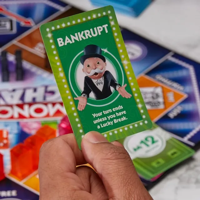 A hand holding up a green Bankrupt card over the board