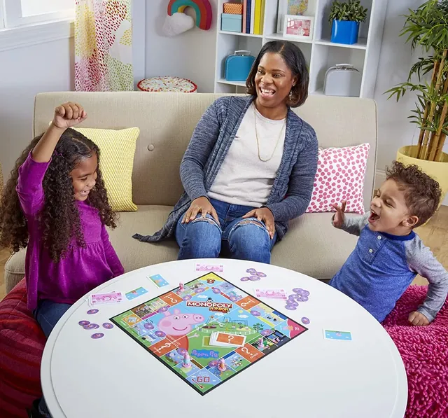 A girl cheering while her mother and brother laugh at the table