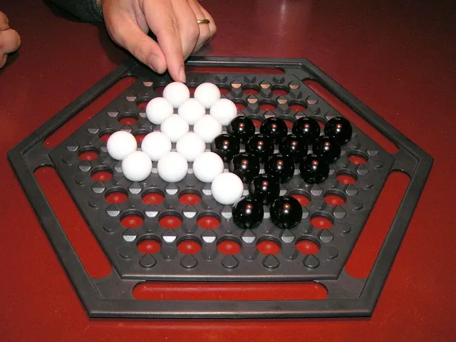 A hand moving white marbles next to black marbles on a hexagonal Abalone board with a red base