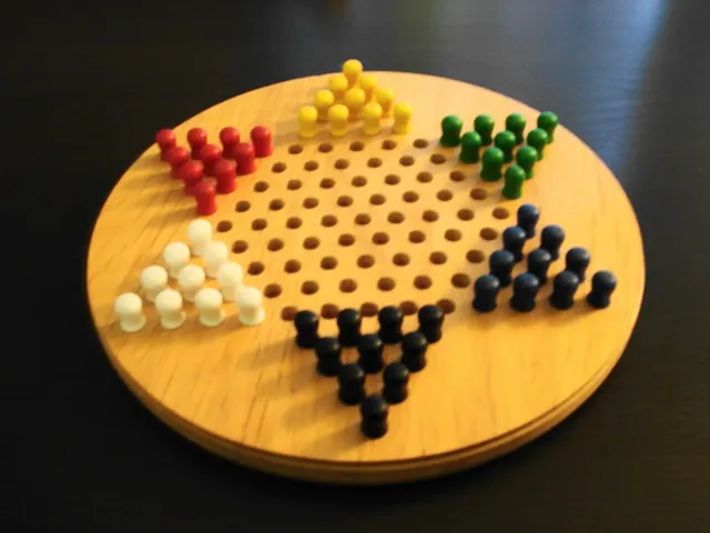 A round wooden board with coloured pegs set out in the points of the star