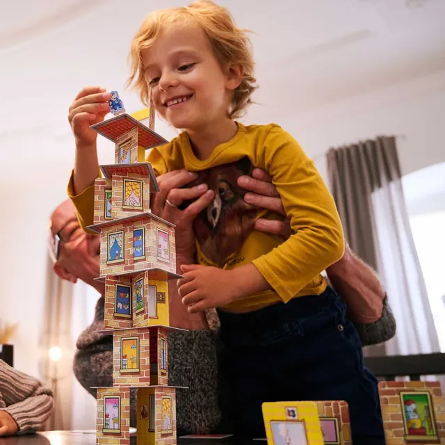 A smiling child beside a Rhino Hero tower many floors high