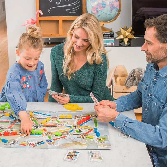 A family of three playing First Journey around a table
