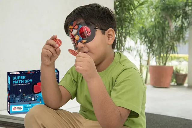 A boy in a green T-shirt holding up a number token while wearing red decoder glasses