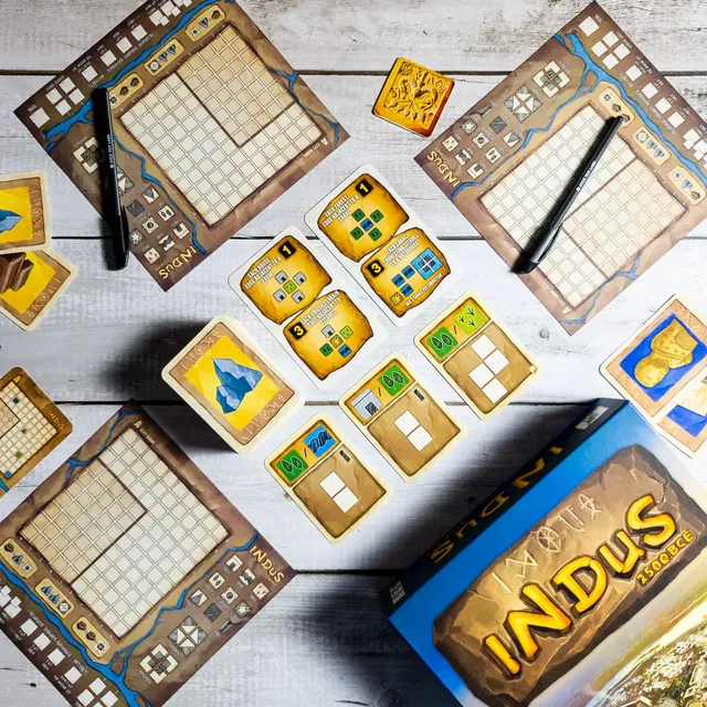 City map sheets, black pens, terrain cards and the box on a white wooden table