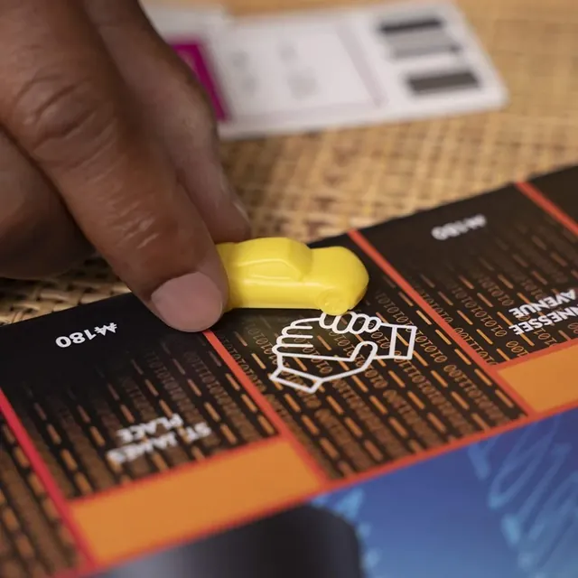 A hand moving the yellow car token onto a space on the board