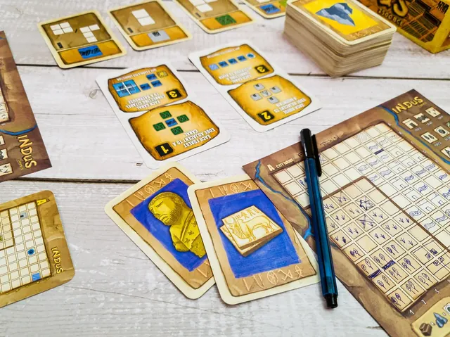 A map sheet being filled in, with a blue pen, resource cards and score cards around it