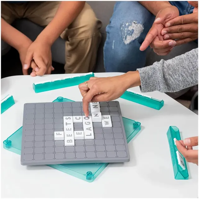 Hands placing a tile on a stack on the grey board, with tile racks around it