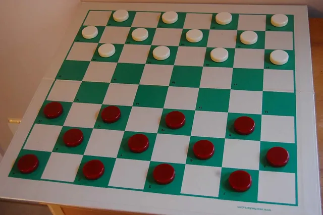 A green and white checkerboard with red and white pieces in their starting places