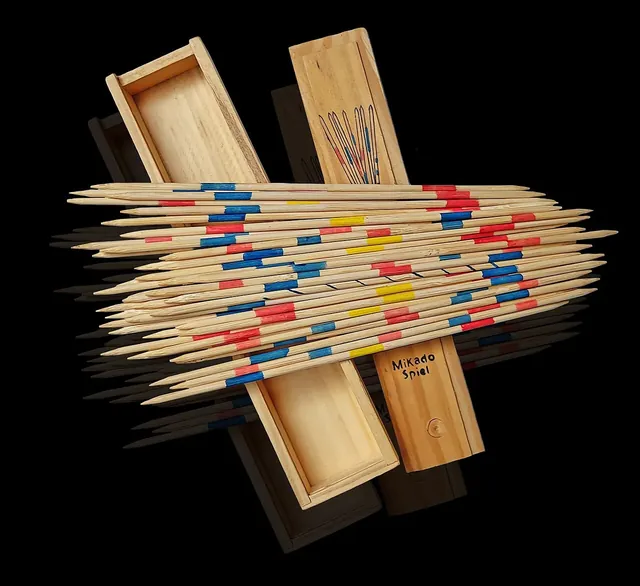 A wooden Mikado box and its lid with a bundle of sticks striped in red, blue and yellow