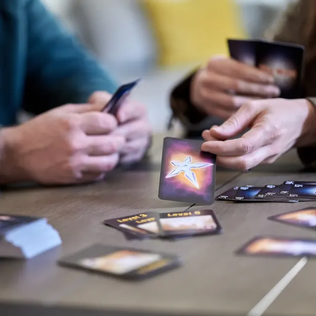 Two players at a table, one about to play a card onto the pile