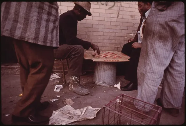 Men playing checkers on an upturned crate on a city pavement
