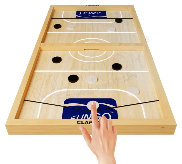 A finger pulling a white puck back against the elastic band, ready to shoot it through the gap in the centre wall