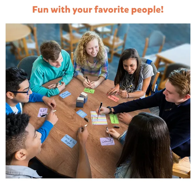 A group of teenagers round a table writing on answer cards, seen from above