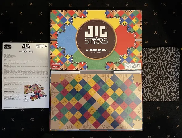 The Jig Stars box, instruction sheet, a finished puzzle of coloured diamonds and the cloth drawstring bag