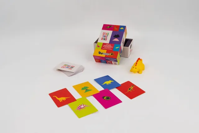 The box with dinosaur cards laid out and a yellow squeaky toy dinosaur