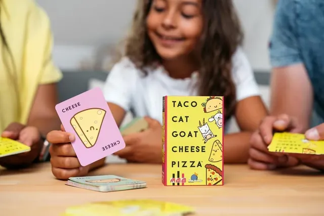 A girl flipping a cheese card onto the pile, with the pack on the table