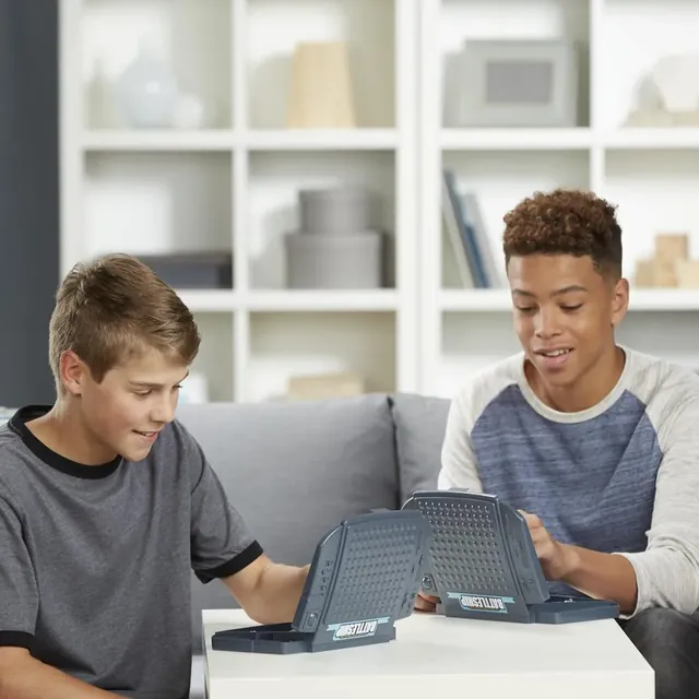 Two boys playing Battleship on a sofa