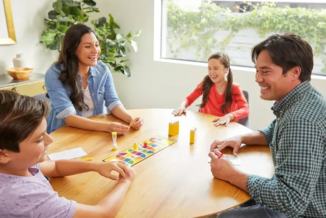 A family laughing around the table while one player guesses