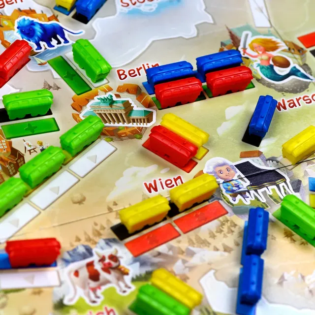 Close-up of the First Journey board: plastic trains on routes between illustrated cities, including Wien