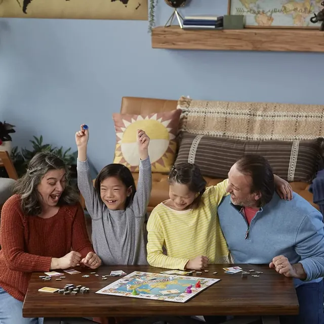 A family of four cheering around the Travel World Tour board on a coffee table