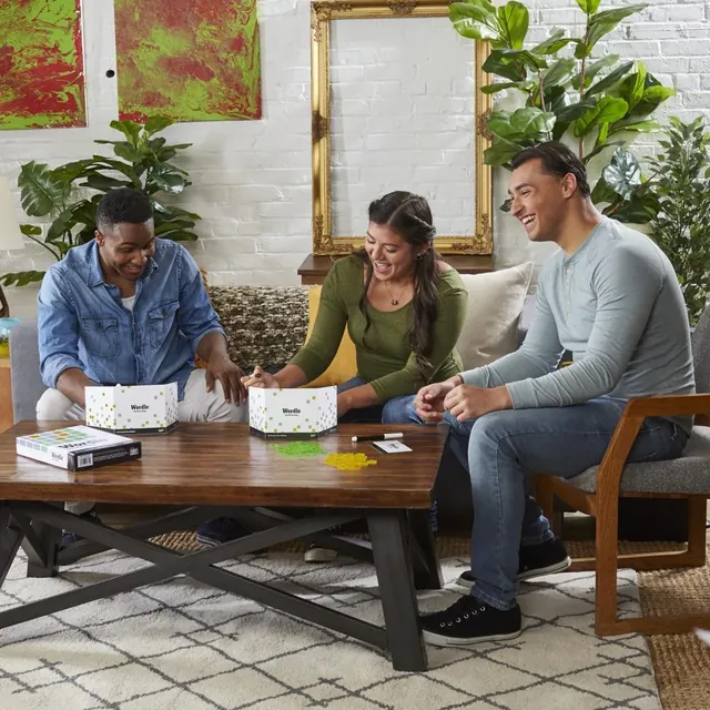 Three adults playing Wordle: The Party Game round a coffee table