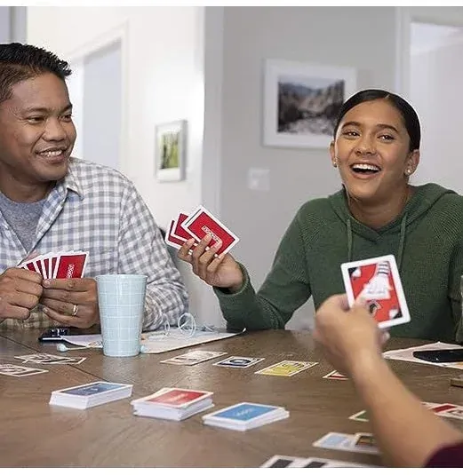 A man and a girl laughing as they play Monopoly Bid at a table