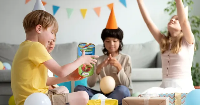 Children at a birthday party in a living room, one holding up the tube