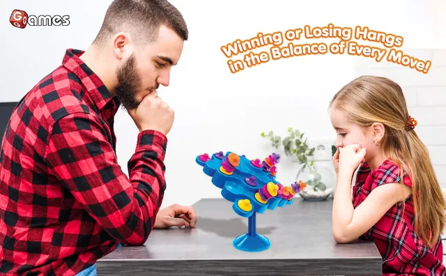 A man and a girl watching closely as a piece is placed on the leaning Topple tower