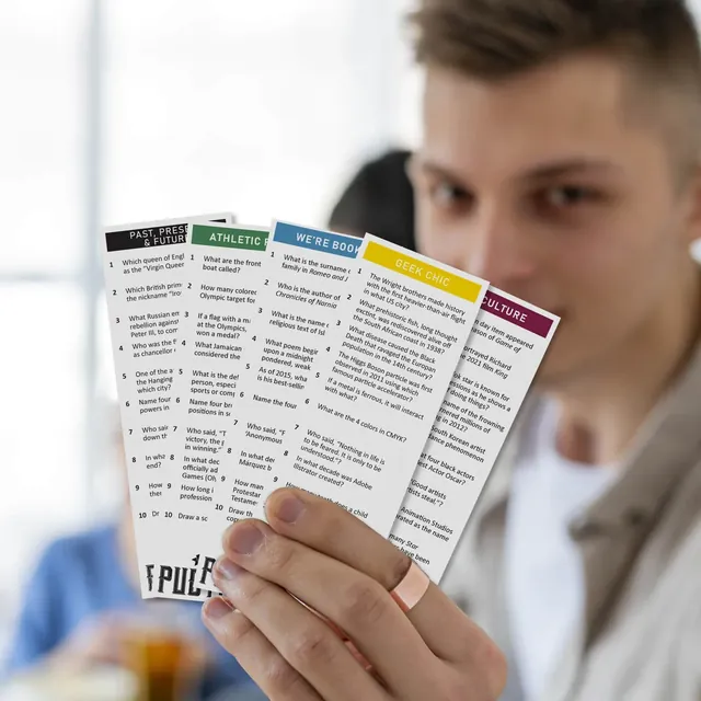 A man holding a fan of Ultimate Pub Trivia question cards