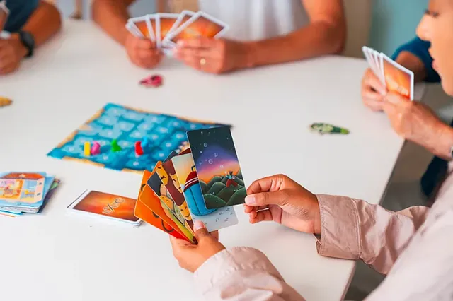 Players holding fans of illustrated cards over the table
