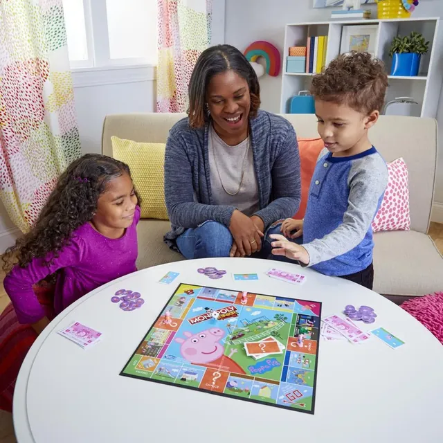 A mother and two children playing Monopoly Junior: Peppa Pig at a round table