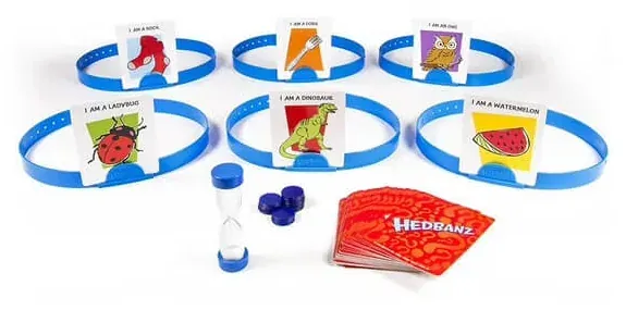 Six blue headbands holding picture cards, with the sand timer, chips and the card deck