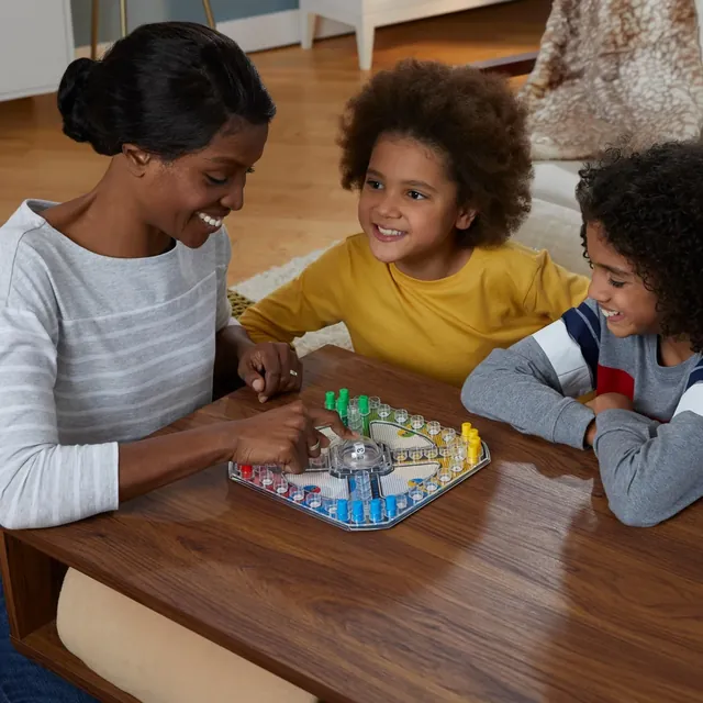 A mother and two children smiling over the Trouble board