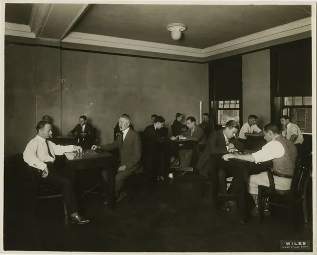 Men in shirts and ties playing checkers at tables in a club room