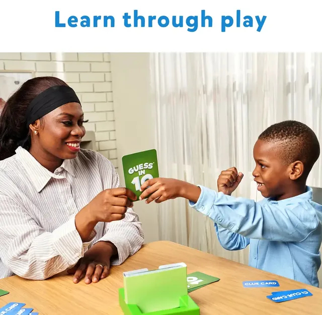 A woman and a boy playing Guess in 10 at a table, the boy holding up a card