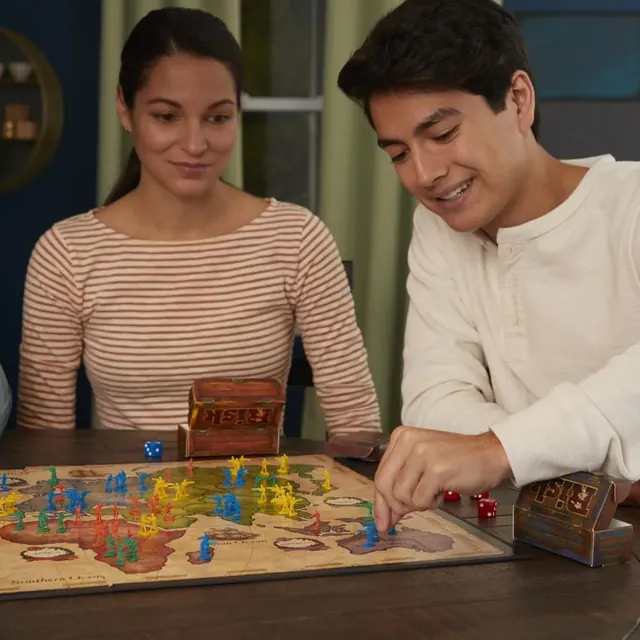 Two players leaning over the Risk map, one moving an army