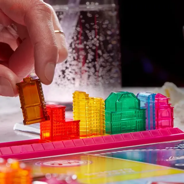 A hand adding a building to a colourful skyline rack