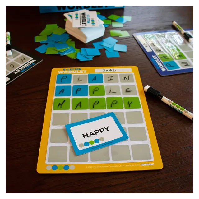 A guessing board with words written in and green and blue chips, beside the secret word card HAPPY