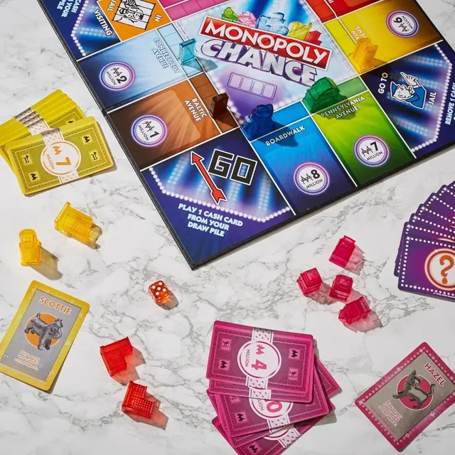 The board on a marble table with cards, buildings and the die spread around it