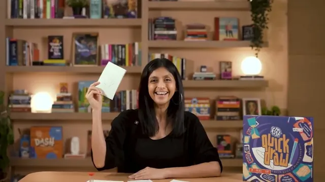Binca's presenter smiling and holding up a drawing, with the Quick Draw box on the table