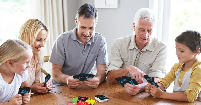 Three generations of a family playing Elemental Blast around a wooden table