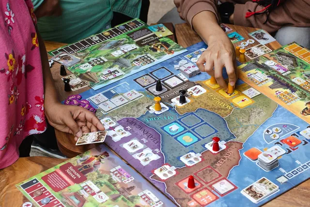 Players' hands placing pawns and tiles on the board during a game