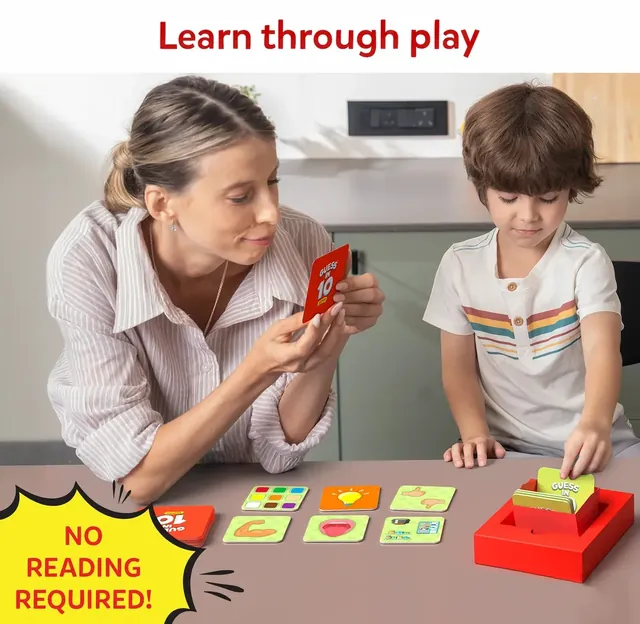 A mother holding up a card for her son, with guider tiles on the table