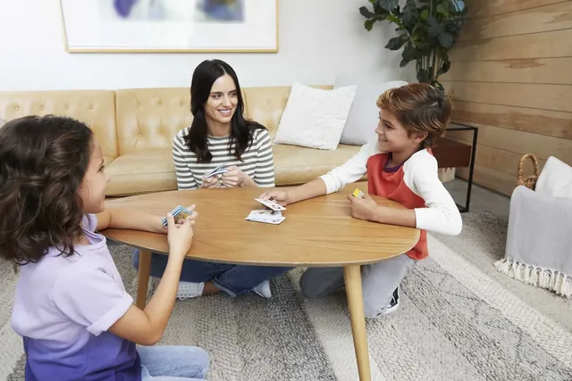 A woman and two girls playing Pic Flip at a low table in a living room