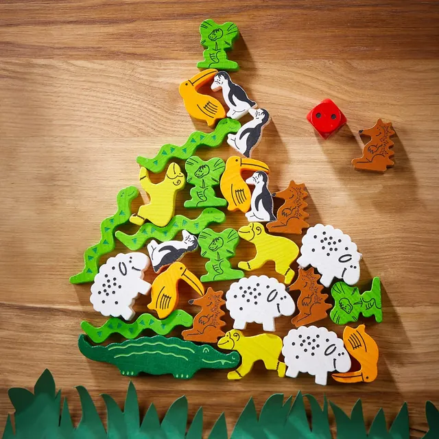 A tall pile of wooden animals balanced on the crocodile, on a wooden table