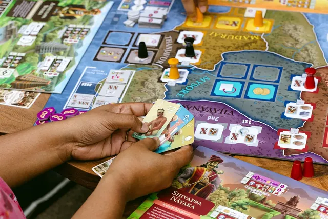 A player holding a fan of artisan cards over the board