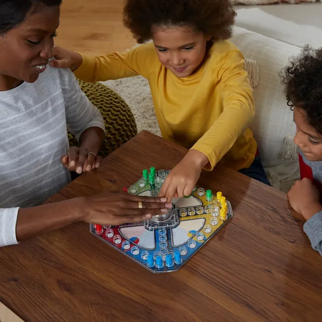 A mother and two children playing Trouble at a wooden table