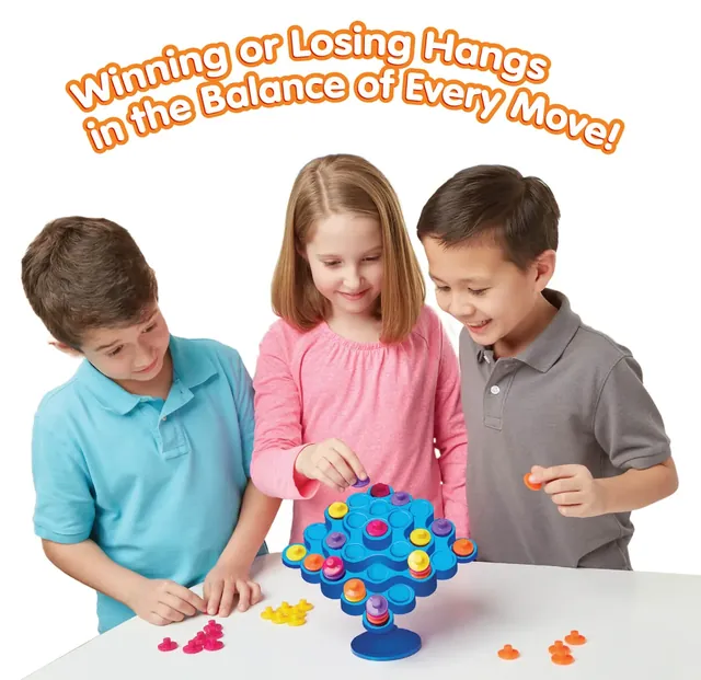 Three children around a Topple tower, one placing a piece while the others watch