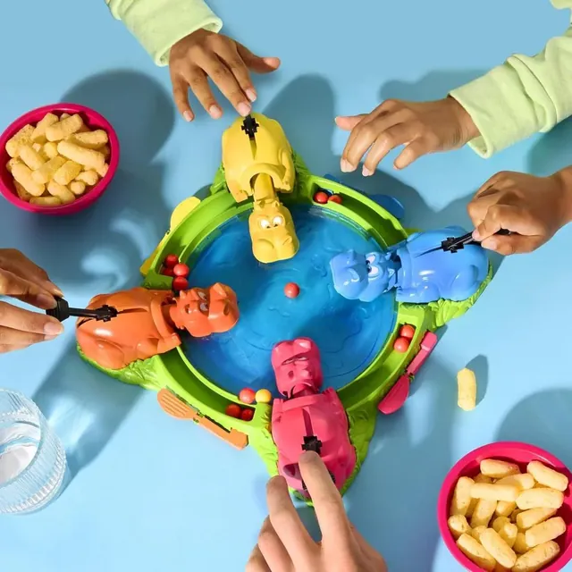 Children's hands pressing the hippos' levers around the pond, seen from above