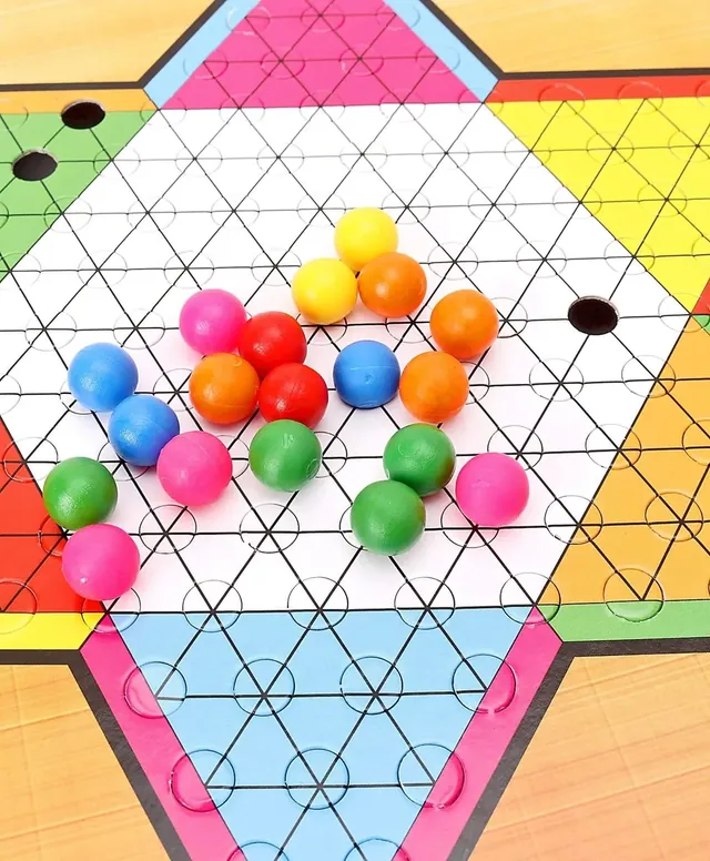 Coloured marbles sitting in the holes of the star board, close up